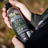 a hunter reading the ingredients on the back of a bottle of hunting body wash and shampoo