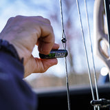 A hand applies string wax and conditioner to a bowstring.