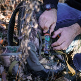 a man's hand pulling the 4oz hunting spray from his hunting bag
