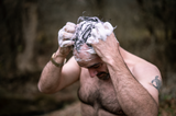 a hunter shampooing his hair in the woods