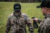 two hunters, one holding the Scent Assassin Natural Earth sprays and spraying the other hunter's clothes
